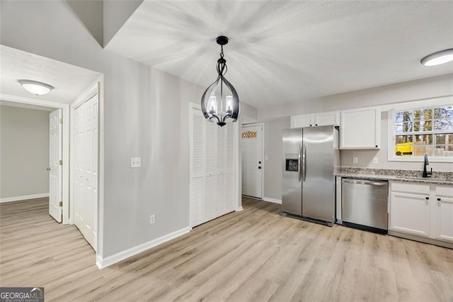 kitchen featuring hanging light fixtures, sink, white cabinets, and appliances with stainless steel finishes