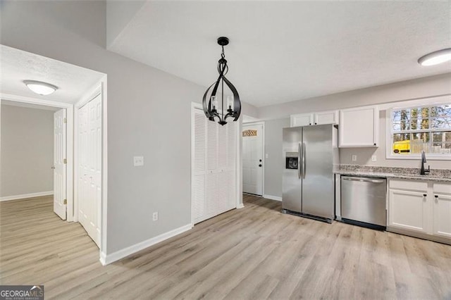 kitchen with stainless steel appliances, hanging light fixtures, sink, and white cabinets