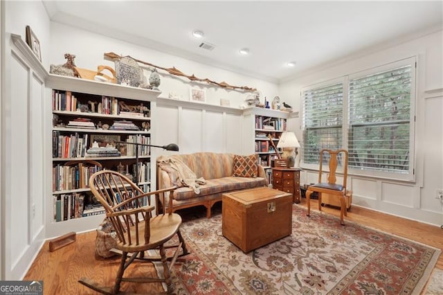 living area featuring hardwood / wood-style flooring and crown molding