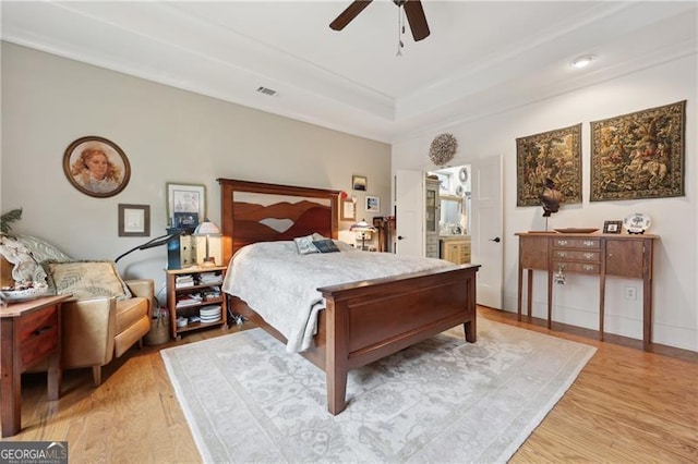 bedroom featuring a tray ceiling, ceiling fan, and light wood-type flooring