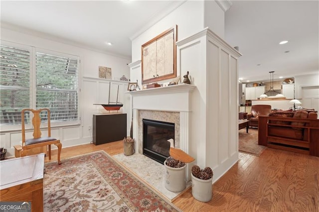 living area featuring a premium fireplace, ornamental molding, and light hardwood / wood-style floors