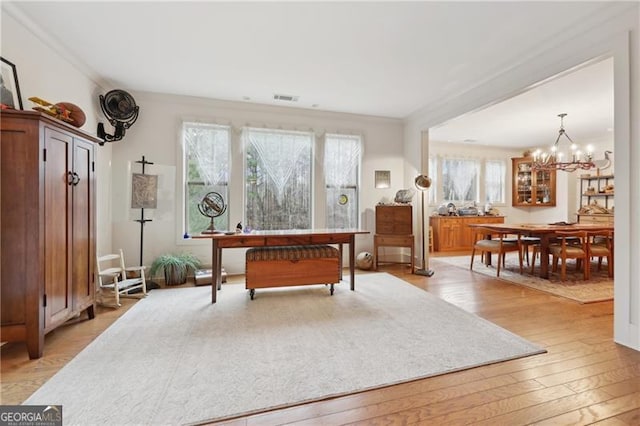 interior space featuring ornamental molding, a notable chandelier, and light hardwood / wood-style floors