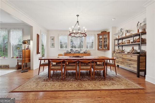 dining area with ornamental molding, wood-type flooring, and a notable chandelier