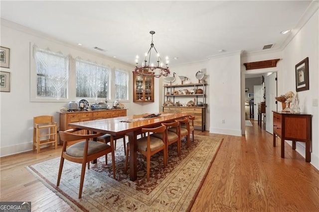 dining room with ornamental molding, a chandelier, and light hardwood / wood-style flooring