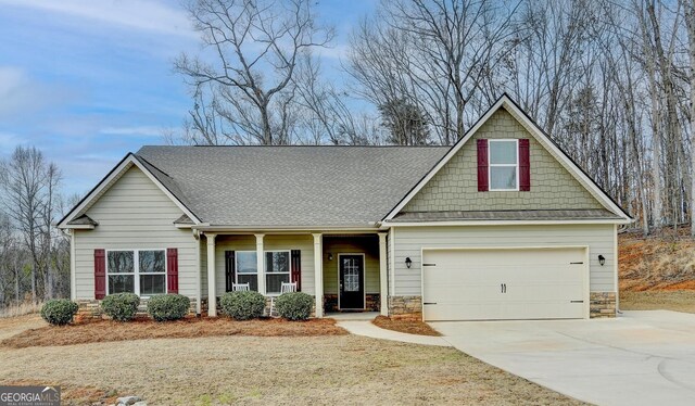 craftsman house featuring stone siding, concrete driveway, a shingled roof, and an attached garage