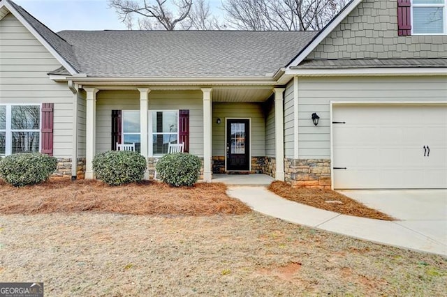 doorway to property featuring driveway, stone siding, a shingled roof, and a porch