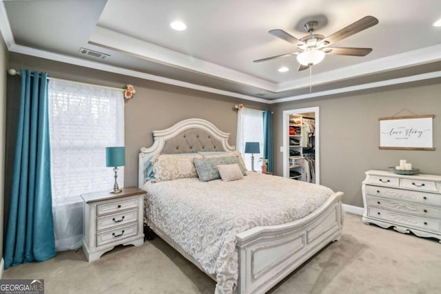 carpeted bedroom featuring a spacious closet, ornamental molding, a raised ceiling, a closet, and ceiling fan