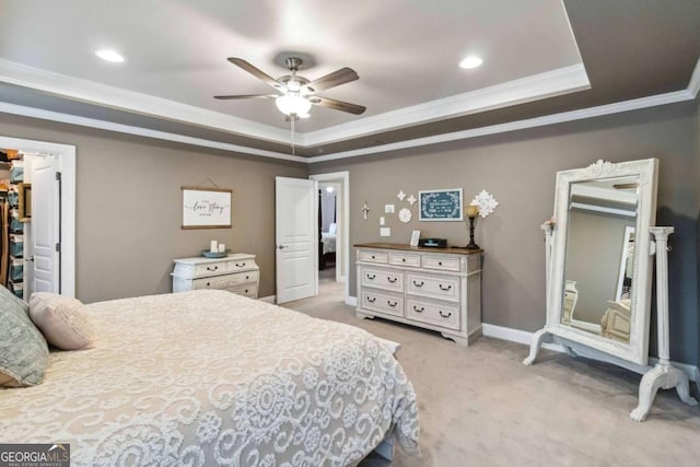 bedroom featuring crown molding, a walk in closet, a tray ceiling, a closet, and light colored carpet