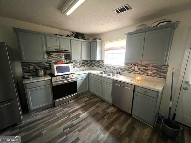 kitchen featuring sink, stainless steel appliances, dark hardwood / wood-style floors, tasteful backsplash, and a textured ceiling