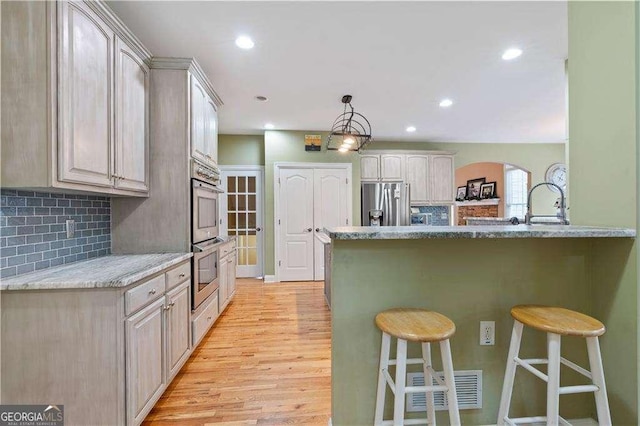 3130 Kates Way NW, Kennesaw, GA 30152 - kitchen with stainless steel appliances, a kitchen bar, light wood-type flooring, backsplash, and recessed lighting