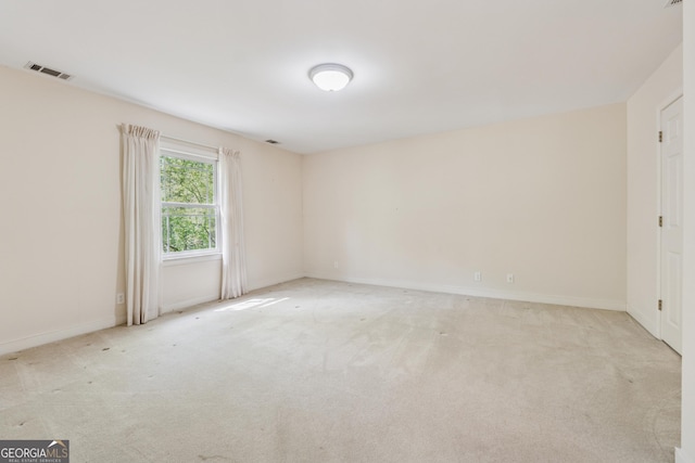 empty room with light colored carpet, baseboards, and visible vents