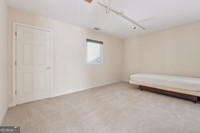 carpeted bedroom with visible vents, baseboards, attic access, and track lighting
