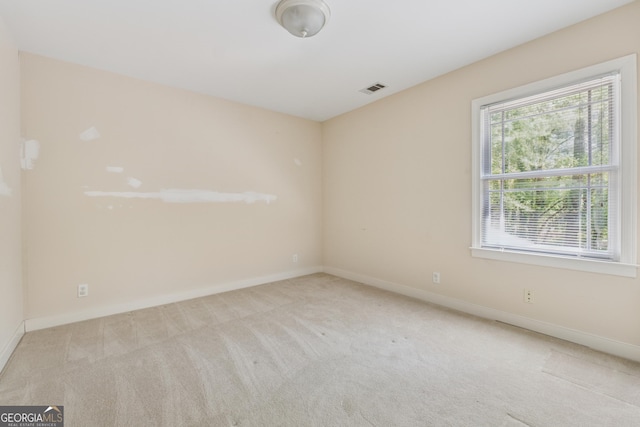 carpeted spare room with visible vents, baseboards, and a healthy amount of sunlight