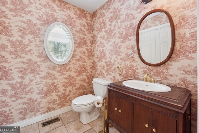 half bathroom featuring vanity, visible vents, toilet, tile patterned floors, and baseboards