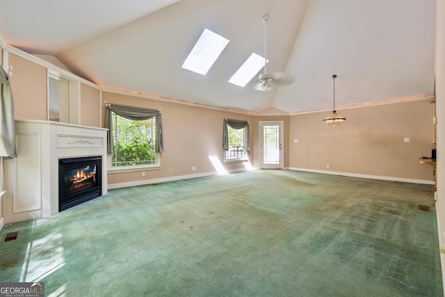 unfurnished living room featuring a glass covered fireplace, carpet, baseboards, and a skylight