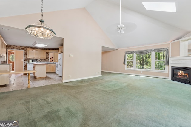 unfurnished living room with baseboards, a ceiling fan, a skylight, a glass covered fireplace, and light carpet