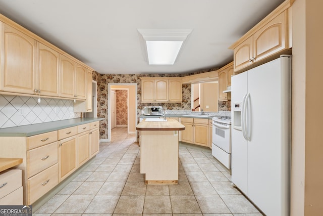 kitchen featuring tasteful backsplash, light brown cabinets, wallpapered walls, white appliances, and under cabinet range hood