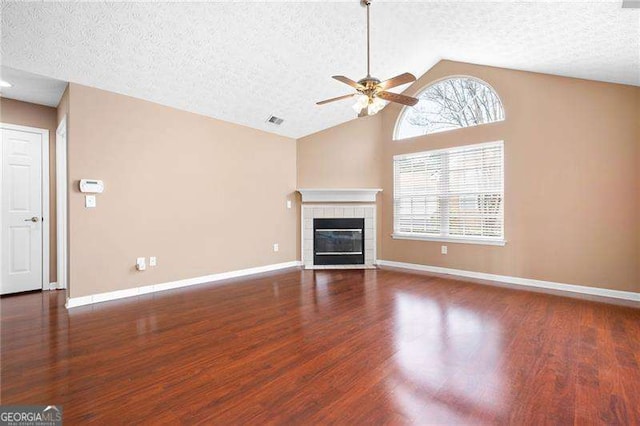 unfurnished living room featuring vaulted ceiling, a tile fireplace, dark hardwood / wood-style floors, and a healthy amount of sunlight