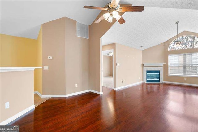 unfurnished living room featuring ceiling fan, lofted ceiling, hardwood / wood-style floors, and a tile fireplace