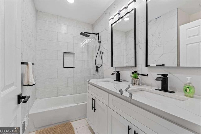 bathroom featuring tile patterned floors, tiled shower / bath, tile walls, vanity, and decorative backsplash