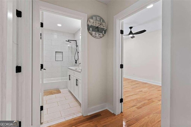 bathroom featuring vanity, ceiling fan, hardwood / wood-style flooring, and tiled shower / bath