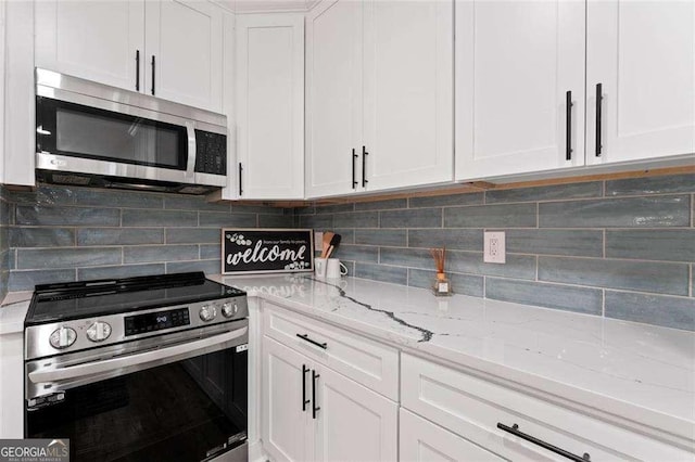 kitchen with light stone counters, stainless steel appliances, backsplash, and white cabinets