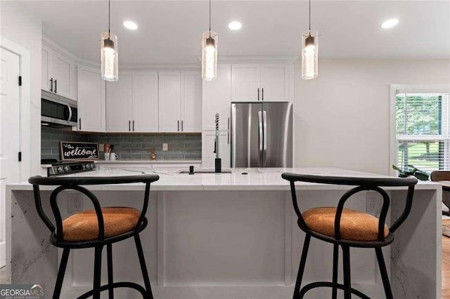 kitchen featuring white cabinetry, light stone counters, decorative light fixtures, and appliances with stainless steel finishes