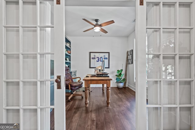 home office with a barn door, dark wood-type flooring, ceiling fan, and french doors