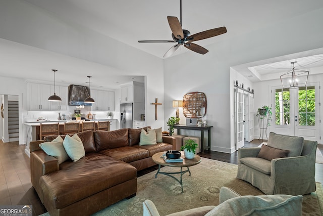 living room featuring dark hardwood / wood-style flooring, ceiling fan with notable chandelier, french doors, and a raised ceiling