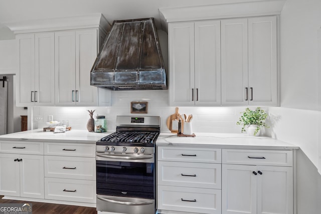 kitchen featuring custom exhaust hood, white cabinetry, stainless steel range with gas cooktop, and decorative backsplash