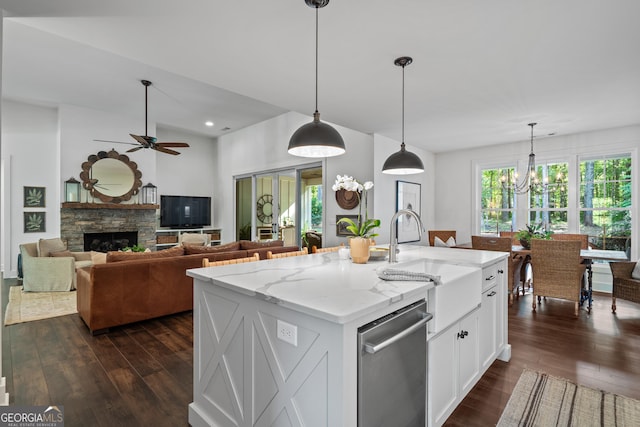 kitchen featuring light stone counters, hanging light fixtures, dishwasher, a kitchen island with sink, and white cabinets