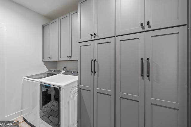 clothes washing area featuring cabinets and washer and dryer