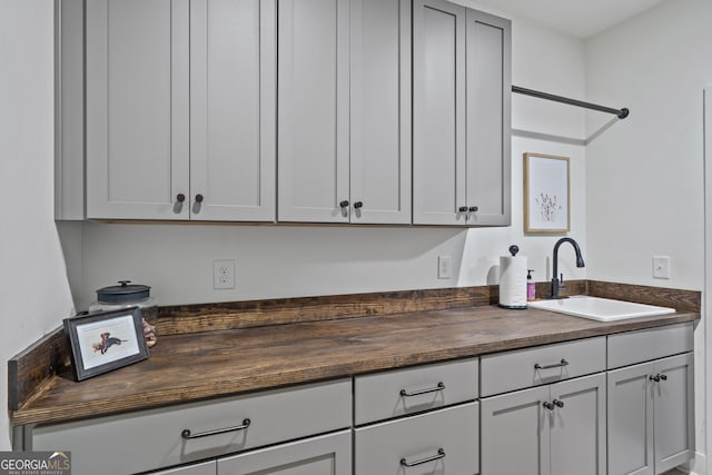 kitchen featuring sink, gray cabinetry, and wood counters