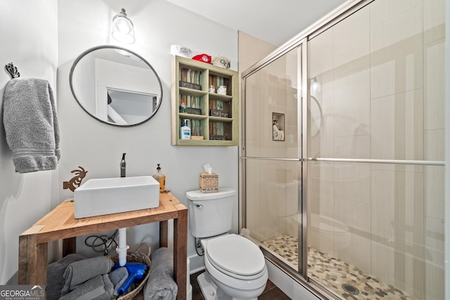 bathroom with toilet, sink, and a shower with shower door