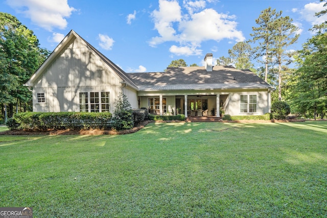 back of property with a yard and covered porch