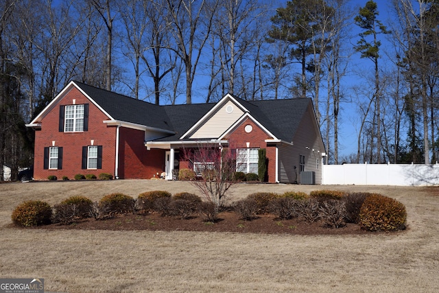 traditional-style home with brick siding, central AC unit, and fence