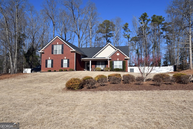 traditional-style home featuring brick siding, a front yard, and fence