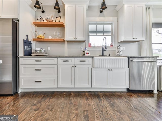 kitchen with dark wood finished floors, white cabinetry, stainless steel appliances, and a sink