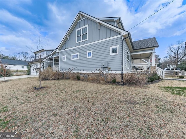 exterior space with a porch, fence, board and batten siding, and a shingled roof