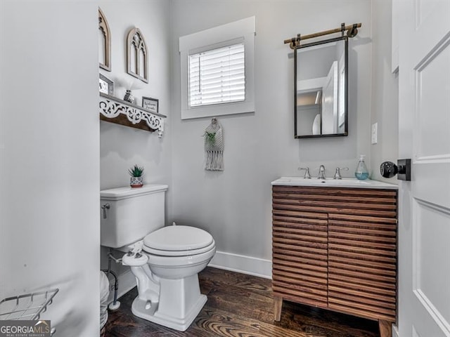 bathroom featuring baseboards, toilet, wood finished floors, and vanity