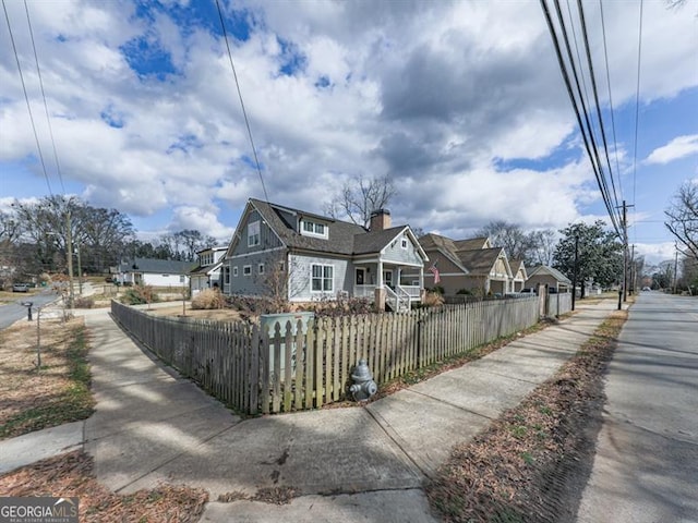 view of front facade featuring a residential view, a fenced front yard, and a chimney