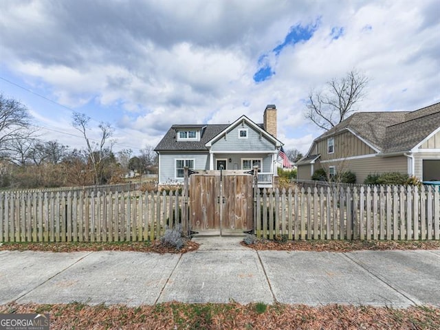 view of front of house featuring a gate, a fenced front yard, and a chimney