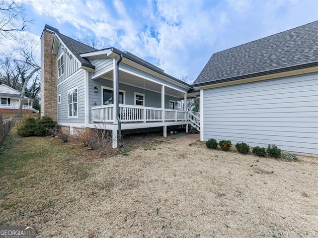 exterior space featuring covered porch, a shingled roof, and fence