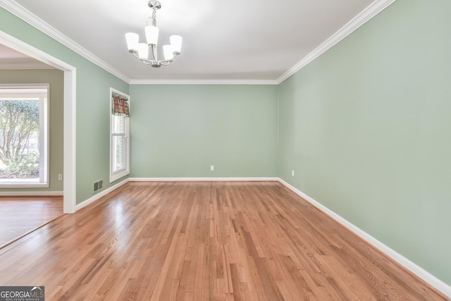 empty room with light wood-type flooring, an inviting chandelier, and crown molding