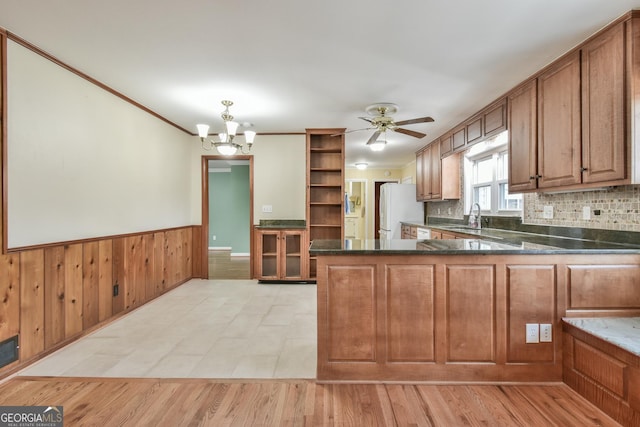 kitchen with light hardwood / wood-style floors, white refrigerator, ceiling fan with notable chandelier, sink, and kitchen peninsula