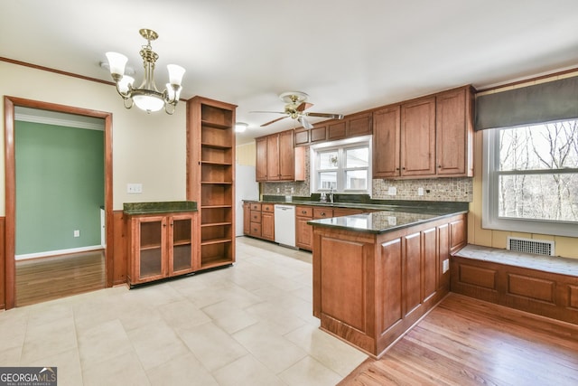 kitchen with sink, backsplash, pendant lighting, white dishwasher, and kitchen peninsula