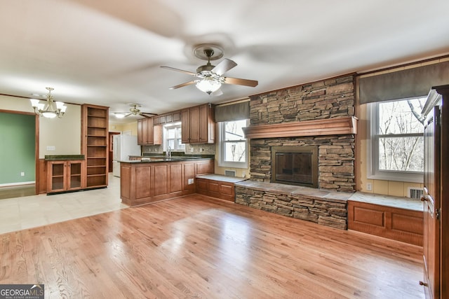 kitchen with light hardwood / wood-style floors, pendant lighting, white refrigerator, sink, and kitchen peninsula