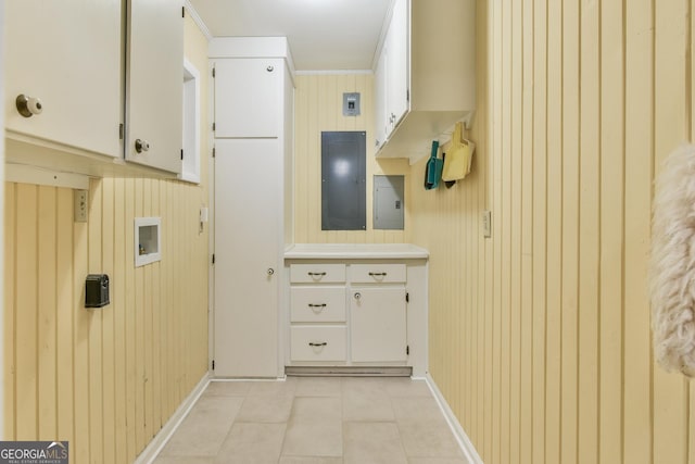 interior space with electric panel, ornamental molding, white cabinets, and light tile patterned floors