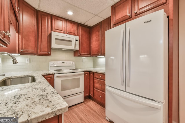 kitchen featuring light wood-type flooring, sink, white appliances, tasteful backsplash, and light stone counters