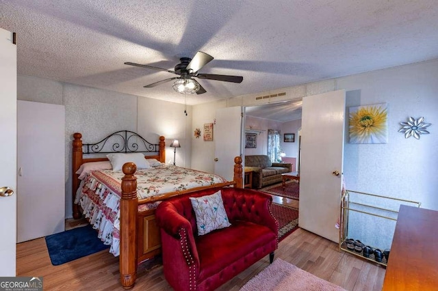 bedroom with hardwood / wood-style floors, a textured ceiling, and ceiling fan